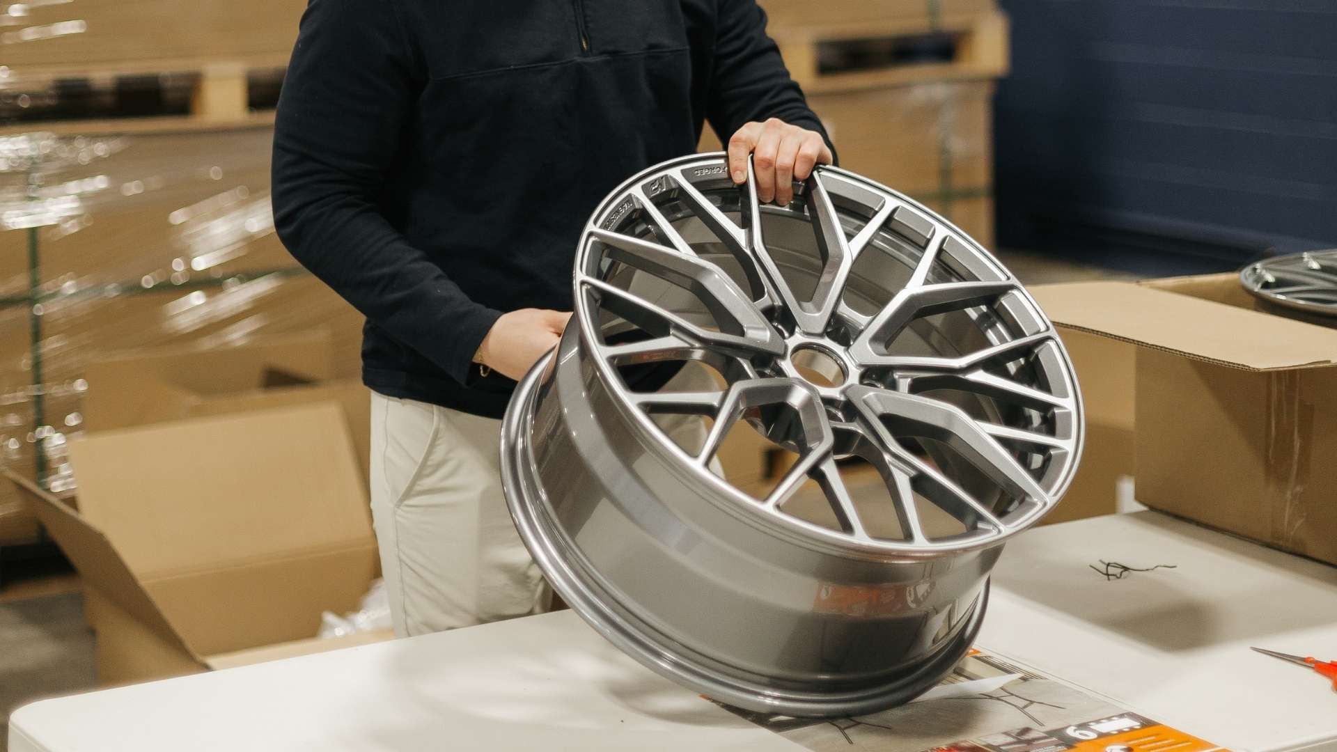 Technician holding a forged magnesium alloy wheel during inspection, demonstrating lightweight forged wheels used for high-performance street and track vehicles